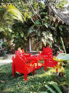 a group of red tables and chairs in the grass at ไทไอดิน in Ban Khui Khwang