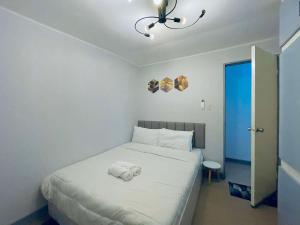 a bedroom with a white bed with a towel on it at RomgelTransientHouseFamily in Abucay