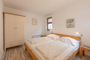 ein Schlafzimmer mit einem Bett mit weißen Laken in der Unterkunft Fischerhaus 316 in Rechlin