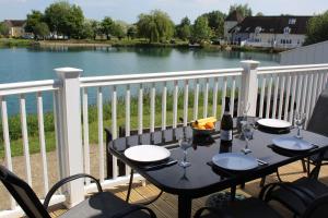 a table on a balcony with a view of a lake at Nyhavn Lakeside Cottage in Cirencester