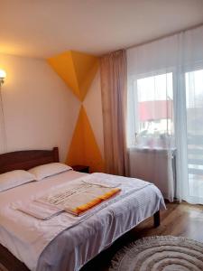 a bedroom with a bed and a large window at Edelweiss Ilinca in Zărneşti