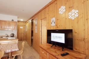 un salon avec une télévision sur un mur en bois dans l'établissement LA TANA - Residence Veronza con piscina, Dolomiti Affitti, à Cavalese