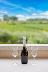 a bottle of wine and two wine glasses on a window at La Casa di Sara in Pacengo di Lazise