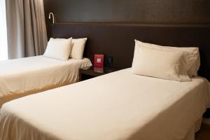two beds in a hotel room with white sheets and pillows at Amérian Córdoba Park Hotel in Córdoba