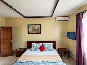 a bedroom with a bed with two red pillows at Pawenzi Ventures Serviced Apartments in Mombasa +48 photos