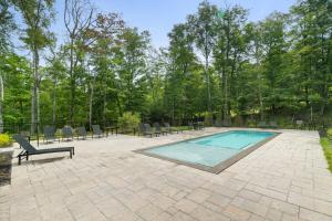 a patio with a swimming pool and chairs and trees at Verbier 6-203 Family Luxury Retreat in Mont-Tremblant