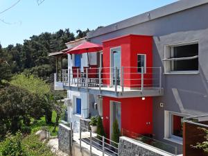 een rood gebouw met een balkon met een rode paraplu bij Casa Del Mare in Kavala