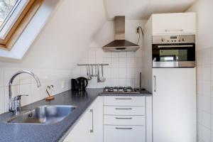 a kitchen with white cabinets and a sink at Gaai I Prachtige Vakantiewoning nabij Bos in Zwiggelte