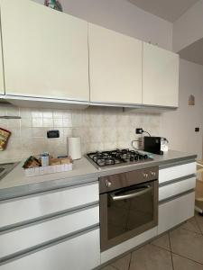 a kitchen with white cabinets and a stove top oven at Appartamento ' Il sole di Vale' in Loano