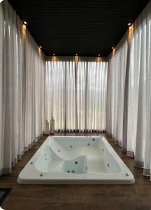 a bath tub in a room with white curtains at Refúgio Paraíso Casa Splendore Spa Panorâmico in Orleans