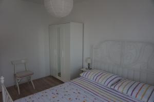 - une chambre blanche avec un lit et une chaise dans l'établissement Apartments Silvija, à Pisak