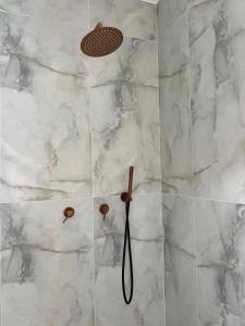 a shower with white marble walls and a shower head at vVצאנז - נופש מפנק in Netanya