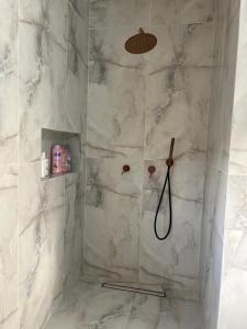 a bathroom with a shower with white marble walls at vVצאנז - נופש מפנק in Netanya