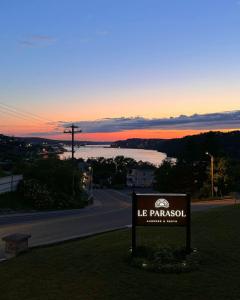 a sign in the grass next to a road with a sunset at Auberge le Parasol in Saguenay