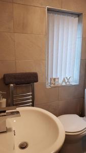 a bathroom with a sink and a toilet and a window at Townhouse @ Birches Head Road Stoke in Stoke on Trent