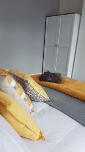 a bed with yellow pillows and a mirror at Townhouse @ Birches Head Road Stoke in Stoke on Trent +2 photos