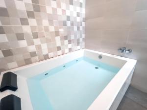 a bath tub in a bathroom with a tiled wall at ISG Apartments Triana Jacuzzi 1 in Seville