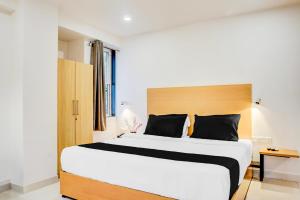 a bedroom with a large bed with a wooden headboard at Super Townhouse Hadapsar Formerly Savali Inn in Pune