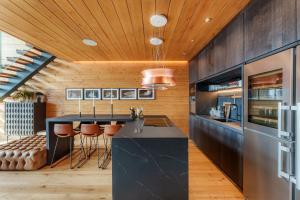 una cocina con una isla negra y techos de madera. en Luxury Mountain Chalet in Sierra Nevada, en Sierra Nevada