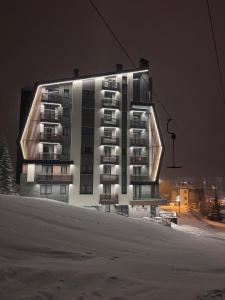 a large apartment building with a lighted facade at night at Apartment25 Poljice Apart Hotel Jahorina in Jahorina