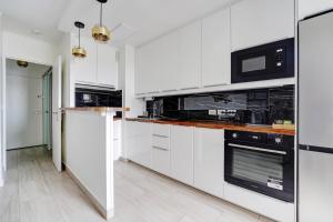 eine Küche mit weißen Schränken und schwarzen Geräten in der Unterkunft Babylone 2 premium in Le Pré-Saint-Gervais + 7 Fotos