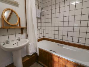 a bathroom with a sink and a bath tub next to a sink at Y Beudy in Llanybydder +17 photos