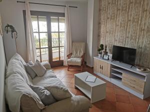 a living room with a couch and a flat screen tv at Apartamento María Platero Céntrico y con las mejores vistas del casco antiguo la montaña y el mar mediterráneo in Frigiliana