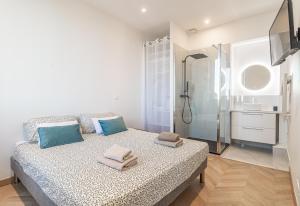 a bedroom with a bed with blue pillows and a shower at T2 Town Center, Casino in Beausoleil