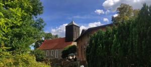 an old brick building with a tower and a church at Pensjonat Stara szkoła in Piaseczno