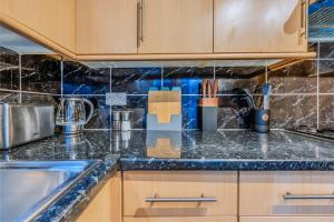 a kitchen with wooden cabinets and a counter top at Pet-friendly flat w/ garden patio & smart tv in Bristol +14 photos