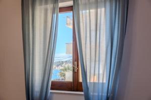 a window with blue curtains with a view of the ocean at Casa Mare Torre San Carlo in Marina di Palma