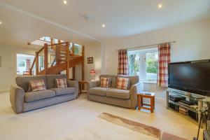 a living room with two chairs and a flat screen tv at Margaret House - Pooley Bridge, Ullswater in Pooley Bridge