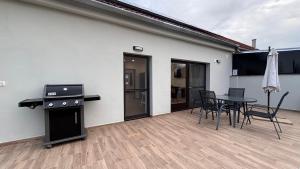 a patio with a table and chairs and a grill at Rózsa Vendégház in Kastélyosdombó