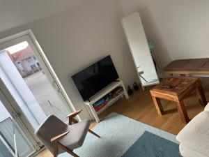 a living room with a flat screen tv and a chair at Cozy little house in Aalborg