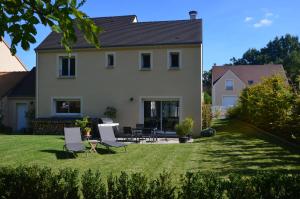 a white house with chairs and a yard at Maison Reine-Claude in Esbly