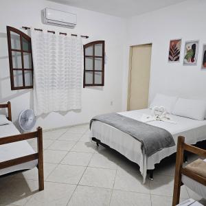 a white bedroom with a bed and a window at Casa tia Rosa hospedagem familiar in Guapimirim +27 photos
