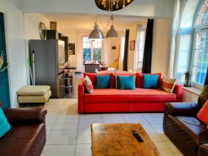 a living room with a red couch with blue pillows at kerwatt - Grande et belle maison de ville avec jardin, proche centre et mer in Cabourg