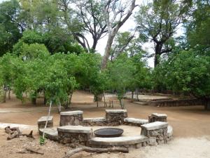 a stone fire pit in a park with trees at Nyime Safari Lodge Campsite in Divundu