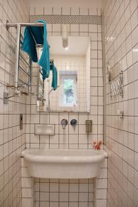 Baño de azulejos blancos con lavabo y espejo en Villa Antoinette, en Saint-Nectaire