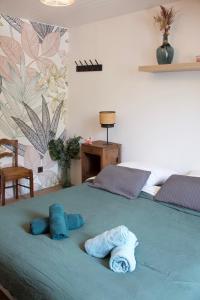 Una cama verde con dos toallas azules. en Villa Antoinette, en Saint-Nectaire