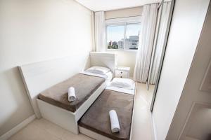 Una pequeña habitación con dos camas y una ventana. en Cobertura com vista panorâmica da Praia da Vila, en Imbituba