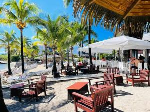 a beach with tables and chairs and palm trees at MANGANAO STUDIO in Saint-François
