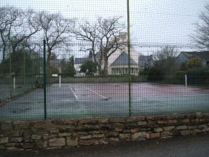 a tennis court with a net on a tennis court at Maison Lallier in Plonevez-Porzay