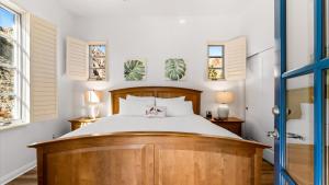 a bedroom with a wooden bed and two windows at LV315 3BR LV Townhome with Mountain Views in La Quinta +36 photos