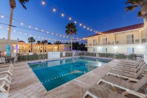 a swimming pool with chaise lounge chairs next to a building at Dunes Inn & Suites - Tybee Island in Tybee Island