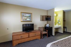 a hotel room with a television on a dresser with a bed at Governors Inn a Travelodge by Wyndham in Pierre