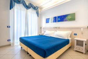 a bedroom with a blue bed and a window at Elaia Garden Hotel in Sperlonga