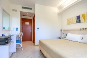 a bedroom with a bed and a desk and a sink at Elaia Garden Hotel in Sperlonga