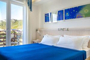 a bedroom with a blue bed and a window at Elaia Garden Hotel in Sperlonga