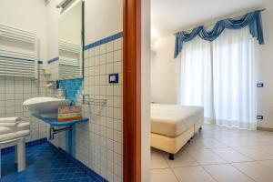a bathroom with a bed and a sink in a room at Elaia Garden Hotel in Sperlonga